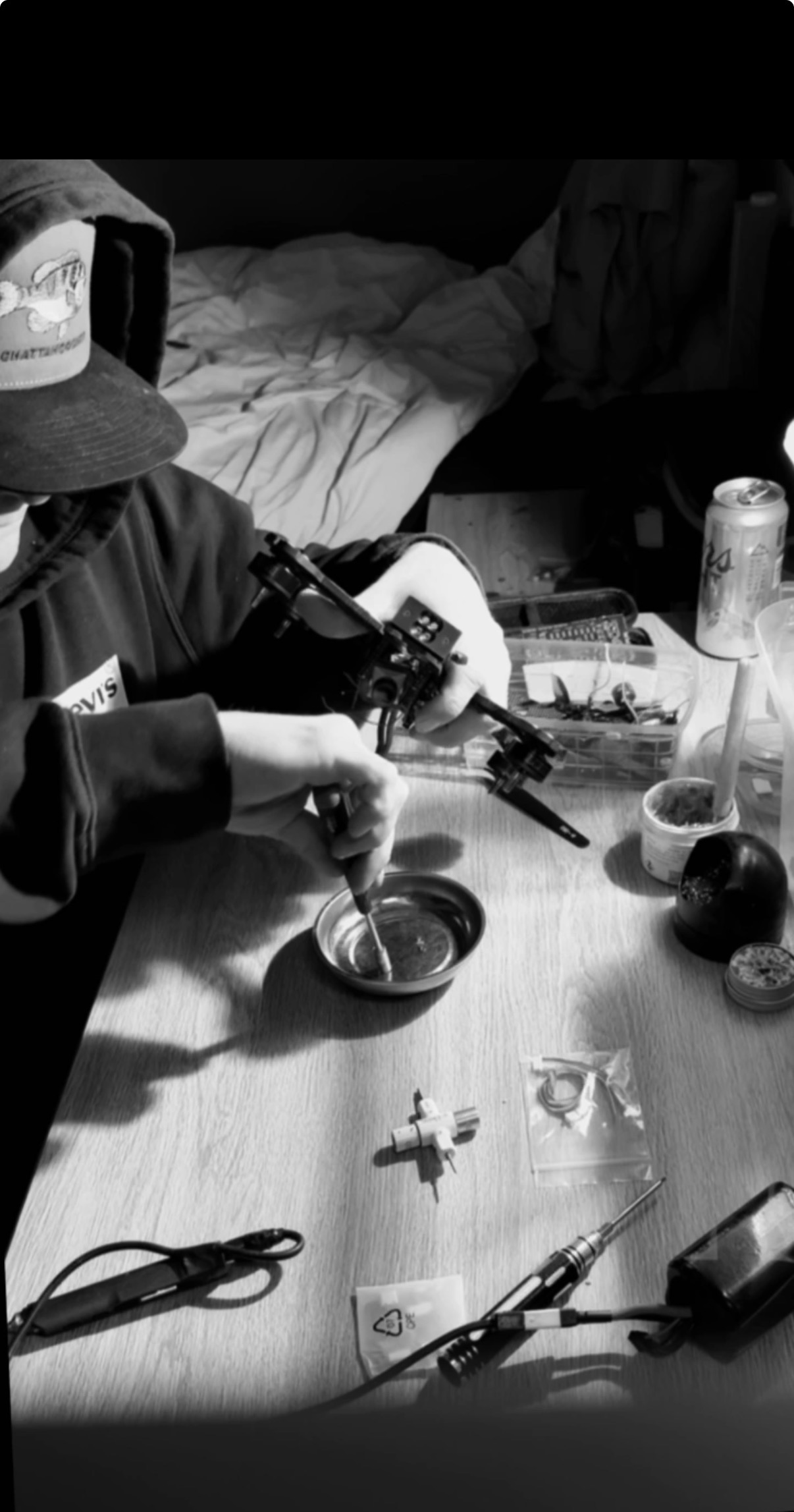 The founder building an FPV quad by hand at the bench, in black and white